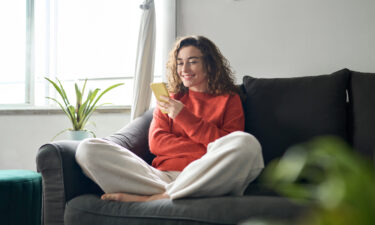 Woman using AI mental health app on smartphone while relaxing on couch at home