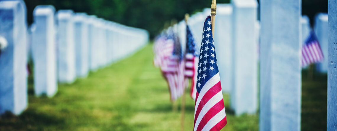American flags placed beside white headstones at a military cemetery on Memorial Day