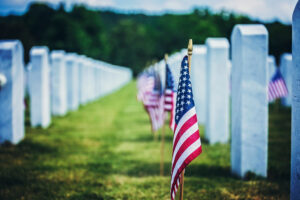 American flags placed beside white headstones at a military cemetery on Memorial Day