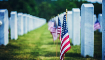 American flags placed beside white headstones at a military cemetery on Memorial Day