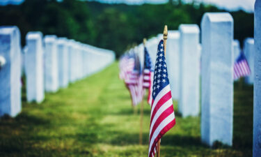 American flags placed beside white headstones at a military cemetery on Memorial Day