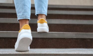 Close-up of a person wearing white and yellow sneakers, walking up concrete stairs, symbolizing the journey of recovery.