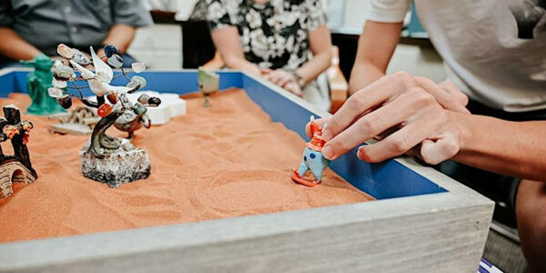 Man playing with figurine in Sand Tray therapy