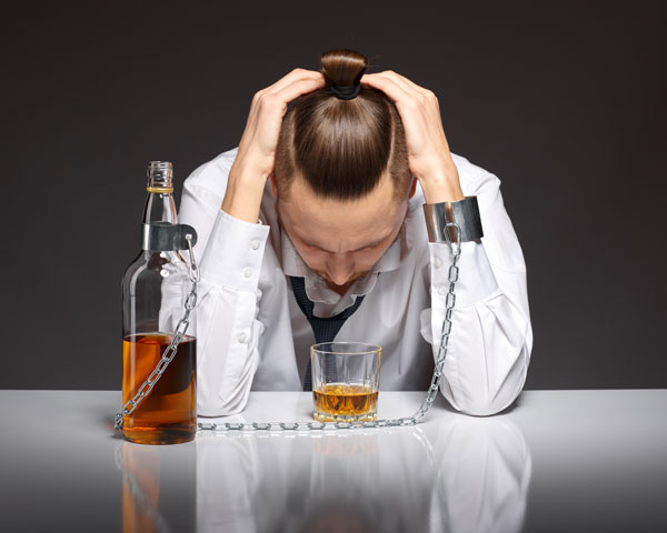 Man with alcohol addiction chained to bottle