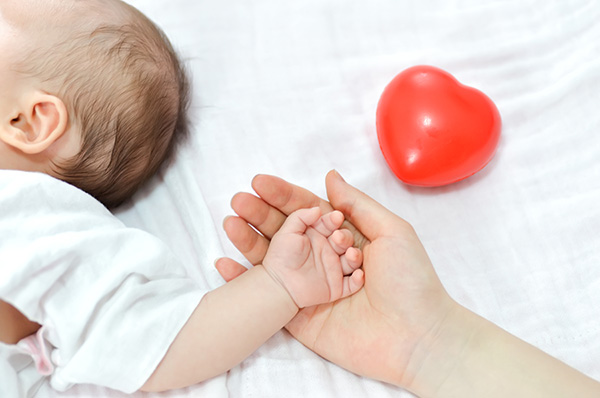 Baby holding mom's hand with heart