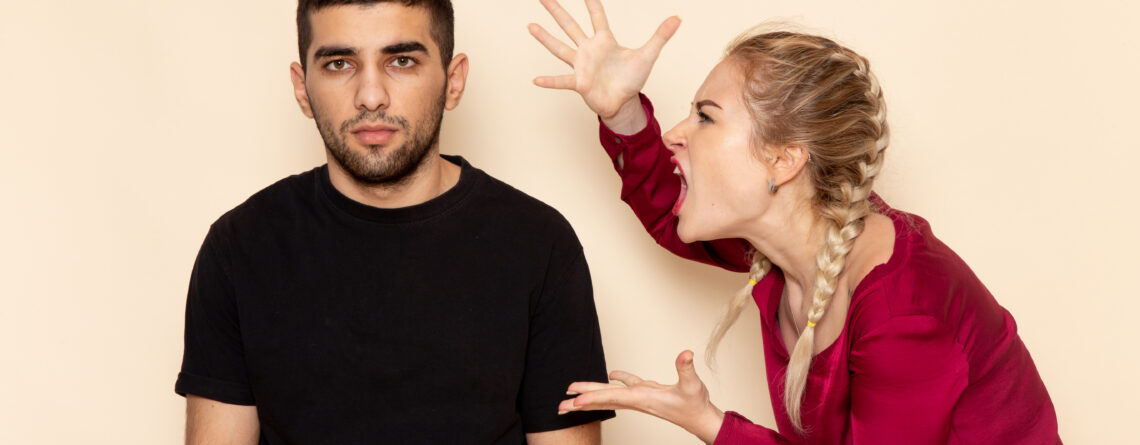 Young woman with red shirt experiencing anger issues and quarreling with man in black shirt.