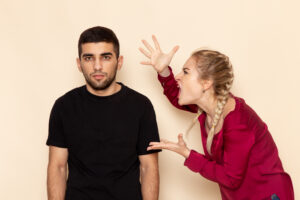 Young woman with red shirt experiencing anger issues and quarreling with man in black shirt.