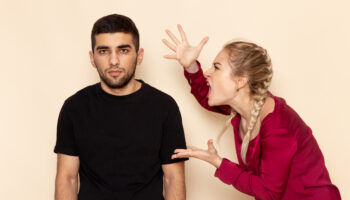 Young woman with red shirt experiencing anger issues and quarreling with man in black shirt.