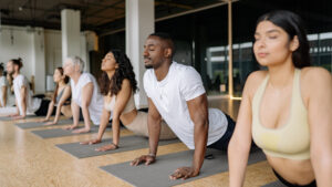 A group of people in a yoga class, eyes closed, doing trauma sensitive yoga.