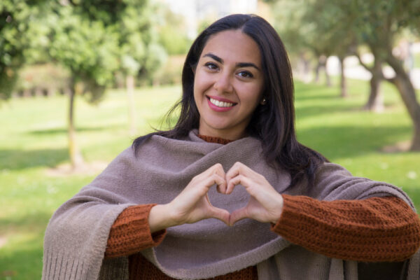 woman holding heart hands outside